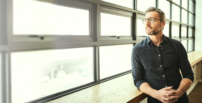 Geschaeftsmann mit Brille schaut aus dem Fenster