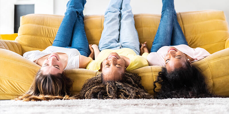 Drei Frauen sitzen kopfüber auf einer Couch. 