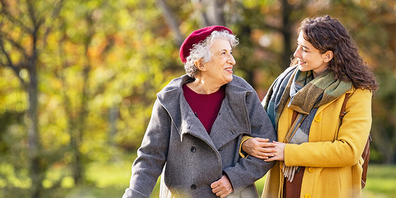 Eine junge Frau hilft einer alten Dame beim Spazierengehen