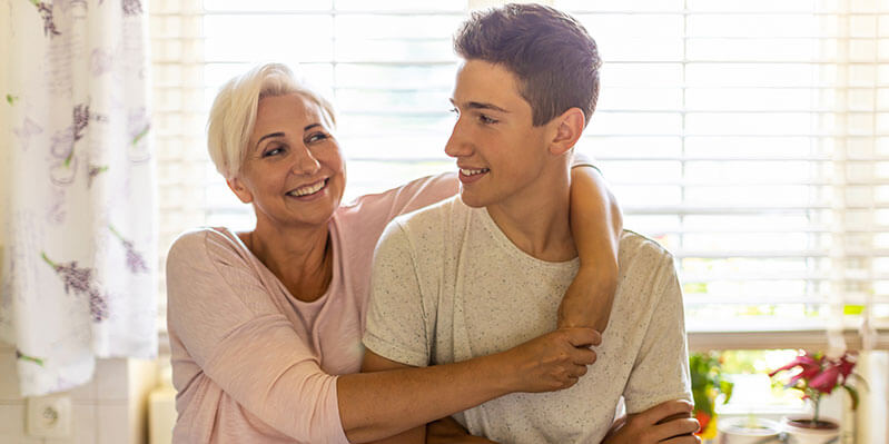 Ein junger Mann wird von seiner Mutter in der Küche umarmt