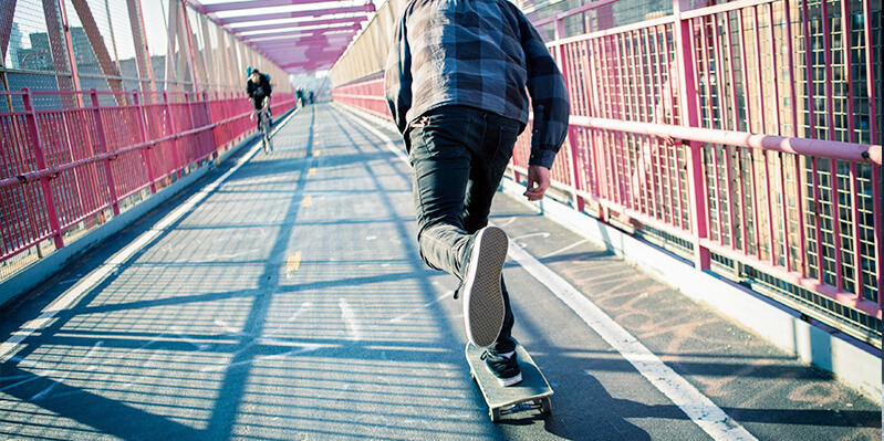Ein junger Mann fährt mit einem Skateboard auf einer Brücke